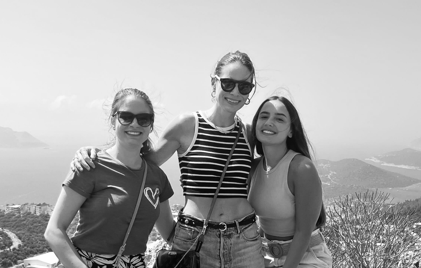 A black and white photograph of Chiara with two of her colleagues, Lilas and Dora. Chiara is standing in the middle with her arms around the other two.