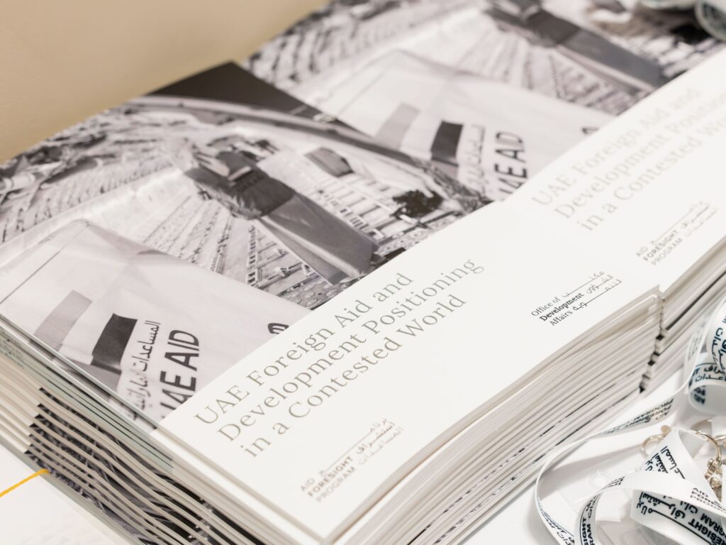 Two stacks of reports, on which the front cover reads "UAE Foreign Aid and Development Positioning in a Contested World"